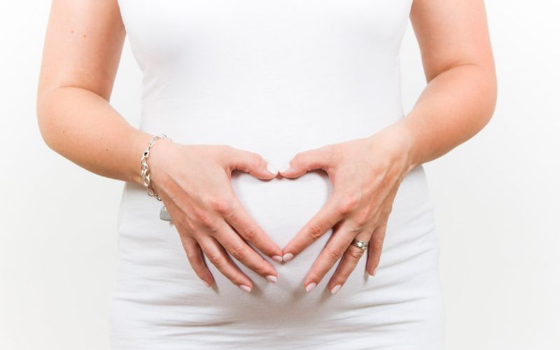 Pregnant woman forming a heart with her hand on her belly